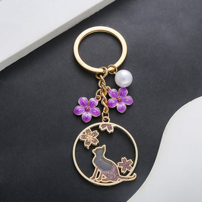 Front product photo of purple cat sakura pearl and flower wreath enamel keychain showing the pictured design arrangement