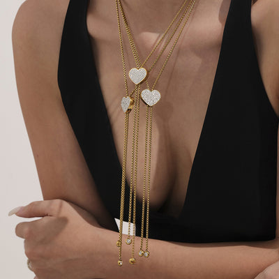 Gold pavé heart slider necklaces worn layered on black top
