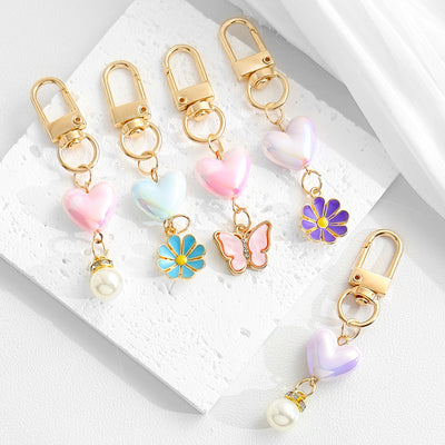 Assorted heart-bead keychains with butterfly, flower, and pearl charms in pink, blue, and purple