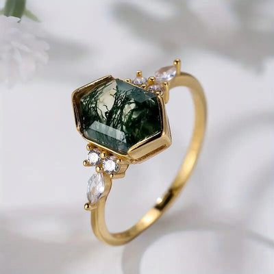 Gold hexagonal moss agate ring angled on soft white background