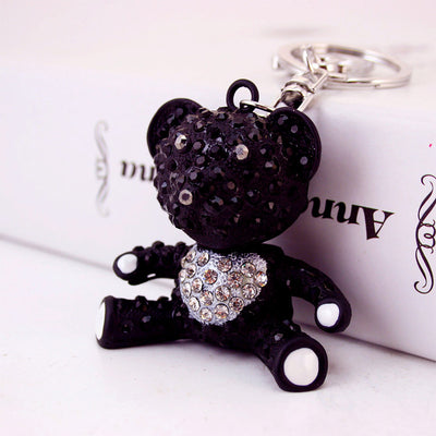 A seated black rhinestone bear keychain displayed beside a white box.