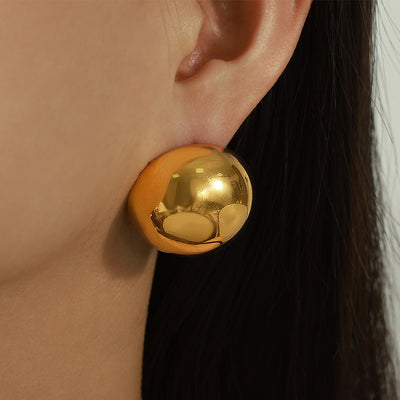 Large gold hollow dome earring worn in close-up profile