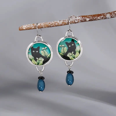 Black cat round cabochon earrings with blue bead drops on branch