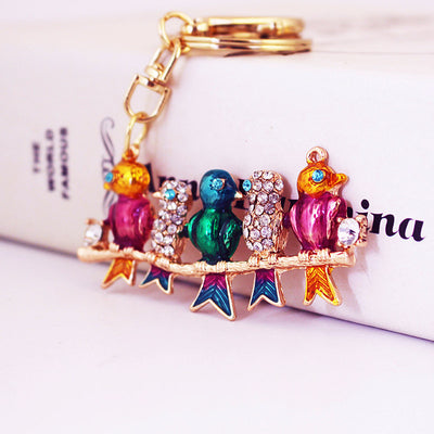 Angled front view of five colorful birds perched on a gold-tone branch.
