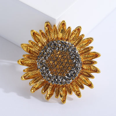 Front view of layered gold tone sunflower brooch with crystal center