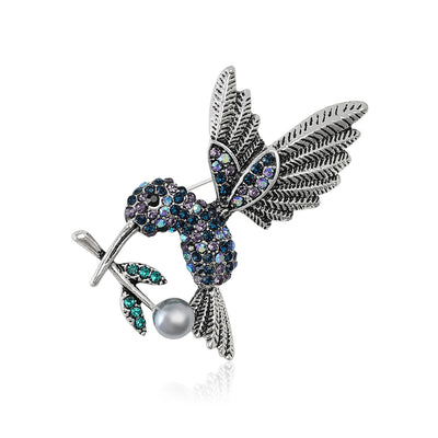 Front view of hummingbird hovering above a flower with multicolor crystals