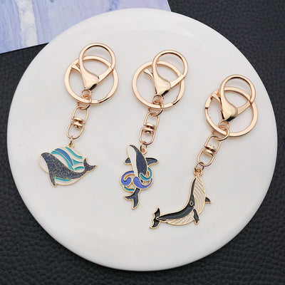 Overview showing the available color and design variations of the blue and black whale ocean metal clasp keychain