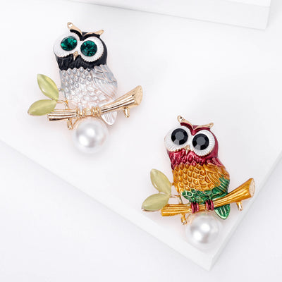 Front view of enamel owl brooch with pearl drop in two colorways