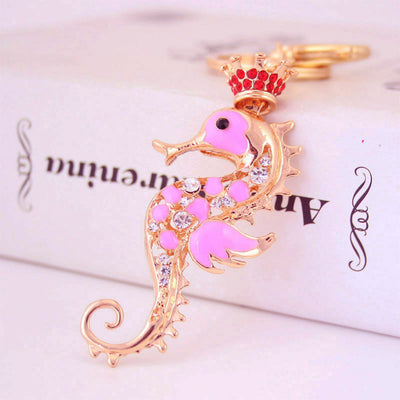 Close-up of a pink crowned seahorse keychain with clear stone accents.