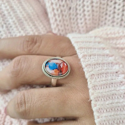 antique silver tone ring showing oval orange and blue color center in a raised frame