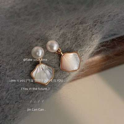 White-pearl-top gold-edged shell-shape drop studs in the first product display.