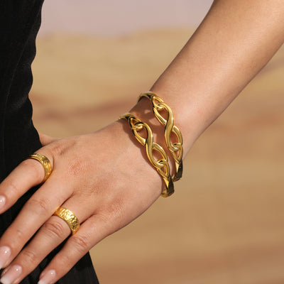 Two gold hollow infinity link bangles stacked on wrist desert setting