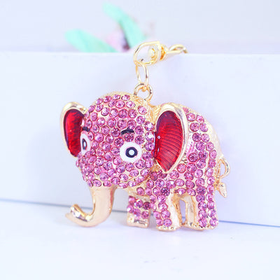 Close-up of a pink rhinestone elephant charm with red inner ears and gold-tone hardware.