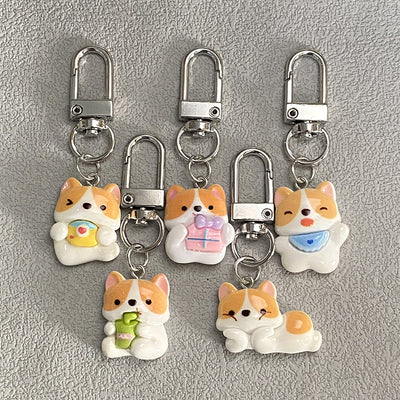 Five resin corgi keychains with silver lobster clasps on gray textured surface