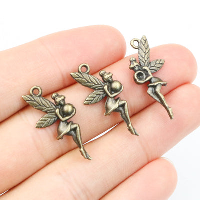 antique bronze winged fairy girl charm assortment on a light background