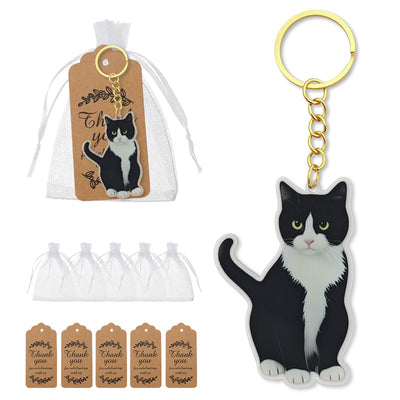 Black-and-white cat keychain shown beside a white drawstring bag and brown thank-you tags.