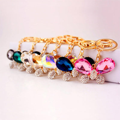 A row of bow keychains displays multiple faceted accent colors and gold-tone rings.