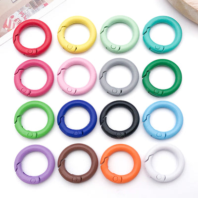 Colorful spring clasp jewelry findings arranged on a light background