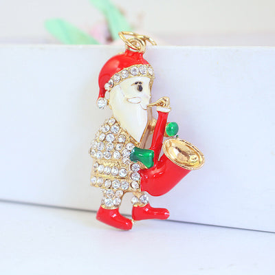 Front view of a rhinestone Santa charm holding a red saxophone against a white background.
