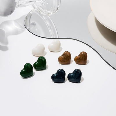 Four pairs of heart studs in white green brown and navy on white