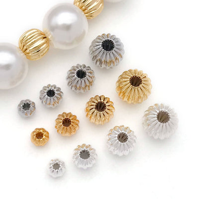 Front overview of vertical fluted hollow pumpkin spacer beads arranged by finish and size