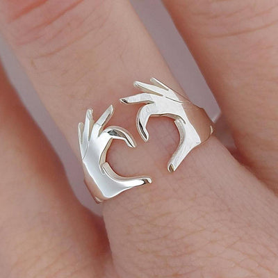 White metal open heart hands ring worn on finger