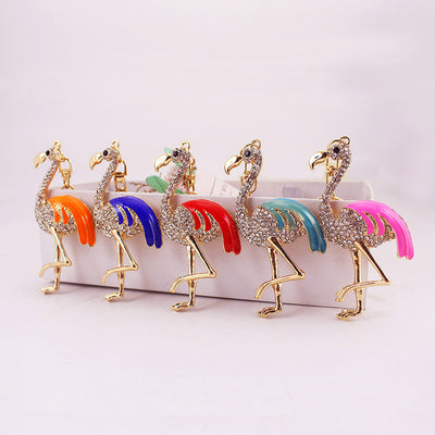 Five gold-tone flamingo pieces with orange, deep blue, red, teal, and pink wings arranged in a row.
