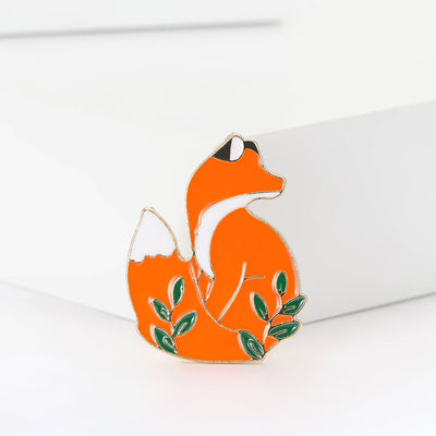 Orange enamel sitting fox brooch green leaves front view
