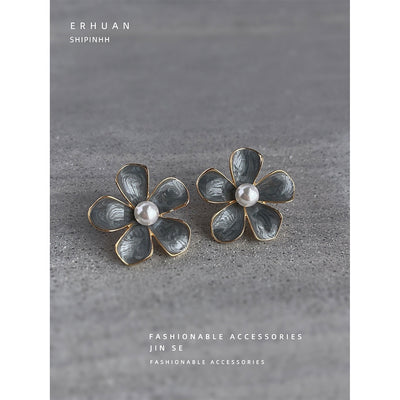 Dusty blue enamel flower pearl studs on gray stone surface