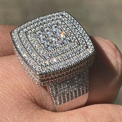 Close-up of silver cushion pavé iced-out statement ring held between fingers