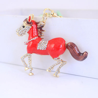 Close view of a glossy red horse charm with clear faceted decoration and a brown tail.