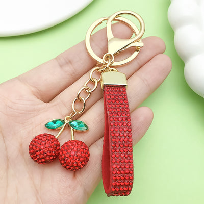 Image 1 showing a person holding a red keychain with two chers.