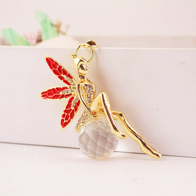 Red-wing fairy charm resting on a faceted clear bead.