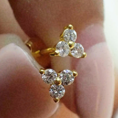 Gold three stone triangle cluster stud earrings held in fingers