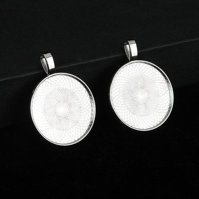 Two round silver-tone bezel pendant trays with side bails on a dark textured surface