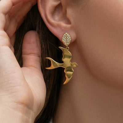 On-ear view of polished swallow drop earrings in main image 1.