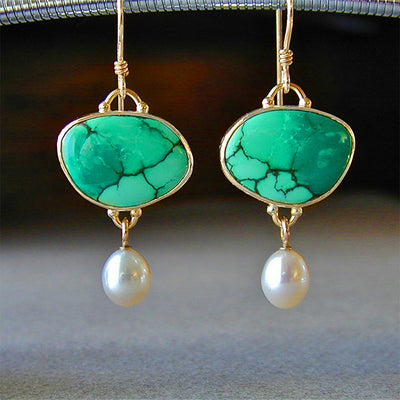 Gold green veined cabochon pearl drop earrings hanging close-up gray surface