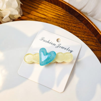 Teal heart on pale yellow cloud glitter hair clip carded