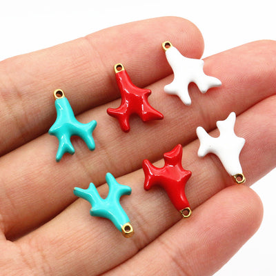 Hand held view of the glossy enamel coral branch charms showing the front shape and finish