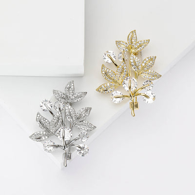 Silver and gold crystal leaf branch brooches on white