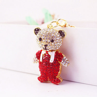 A red rhinestone bear keychain stands beside a white display with its clasp visible.