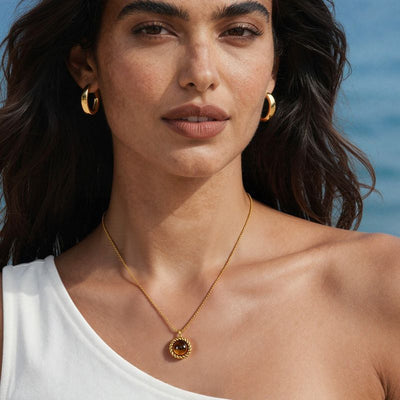 Model at beach wearing gold tiger eye round pendant rope necklace