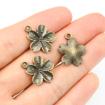 Antique Bronze Six-Petal Flower Alloy Charm Pendant, grouped overview on a plain background