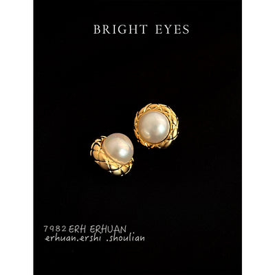 Gold-tone round pearl stud earrings on a black display.