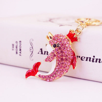 Close-up of a pink crowned dolphin keychain with pink rhinestones and red fins.