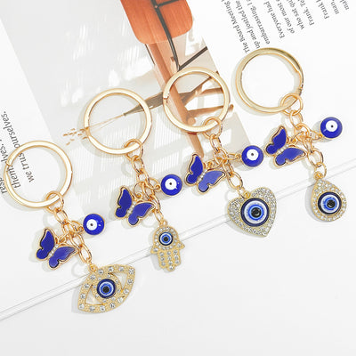 Several gold keychains with blue butterflies eyes and crystal pendants