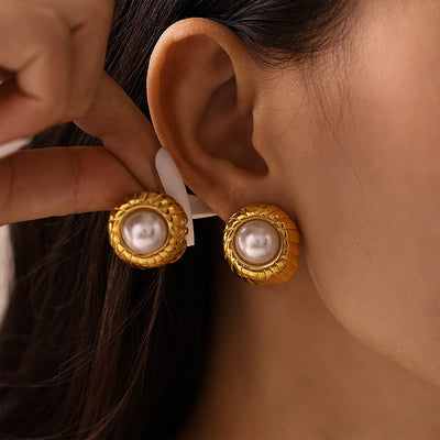 Gold ribbed shell imitation pearl studs worn and held near ear