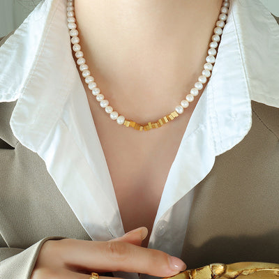 Model wearing white pearl necklace gold square bead center