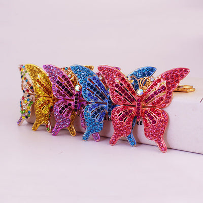 Five butterfly keychains in multicolor, gold, purple, blue, and pink are arranged in a row.