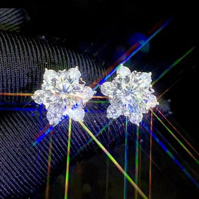 Pair of silver crystal flower snowflake studs on dark fabric with light rays